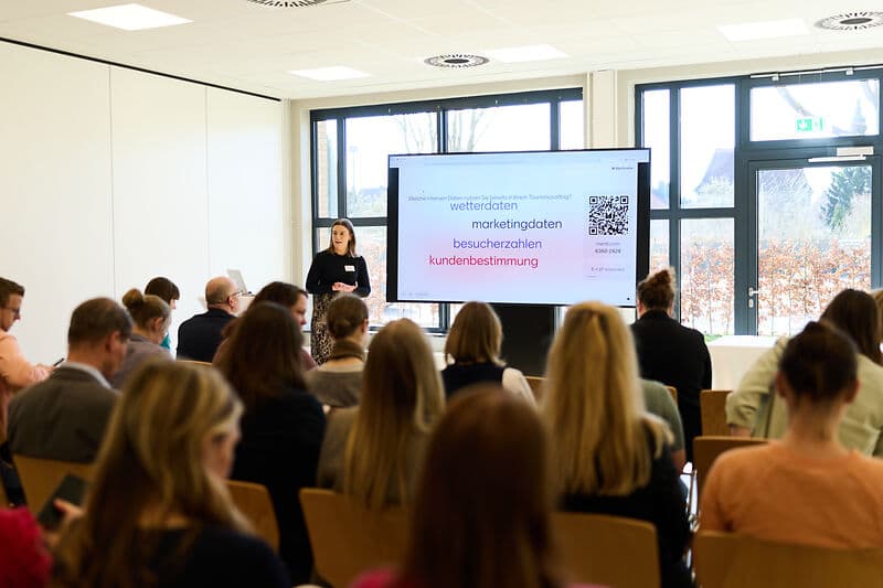 Personen sitzen in einem Workshop, die Rednerin erläutert die Inhalte.