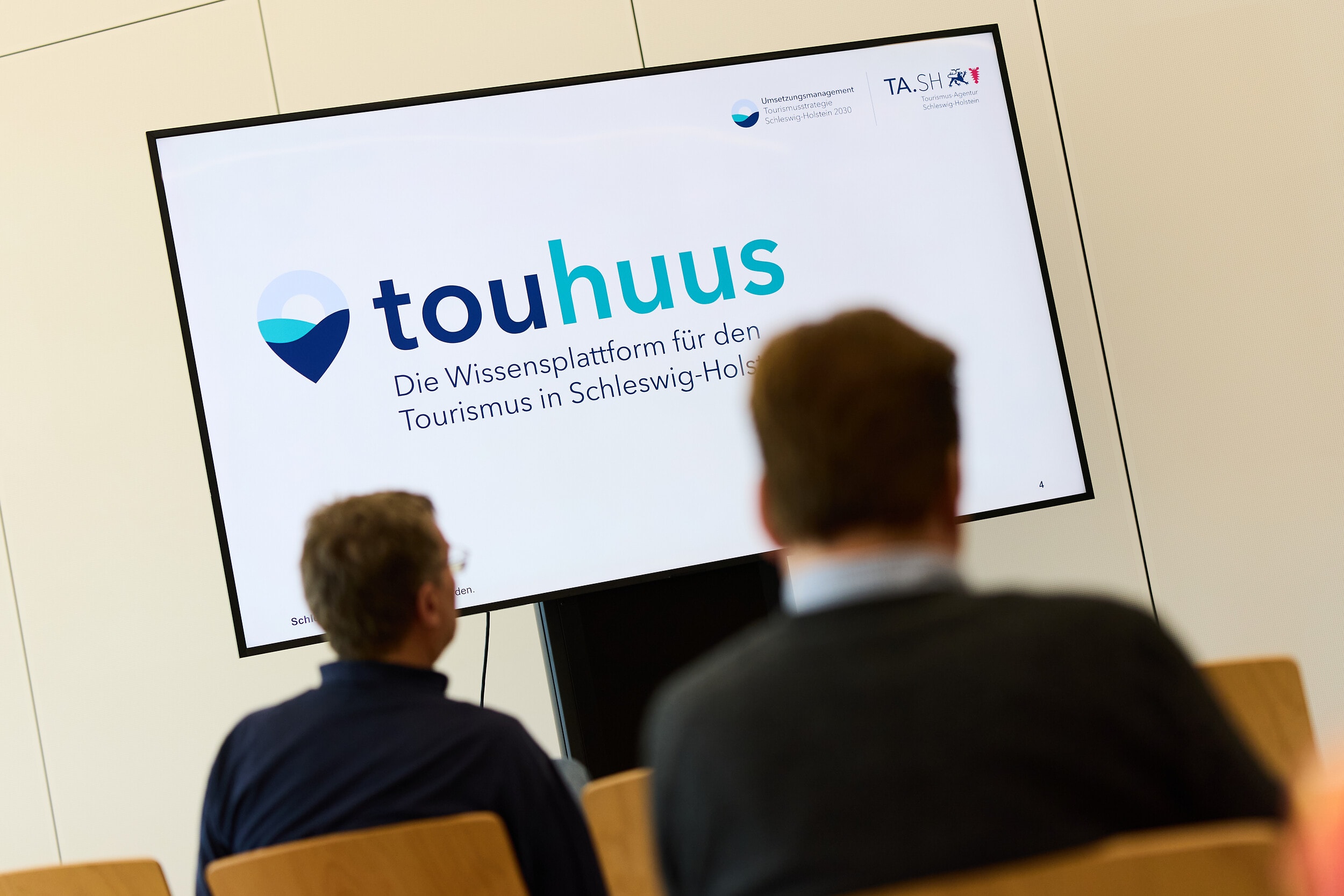 Bildschirm mit Anzeige "touhuus" vor Zuschauern