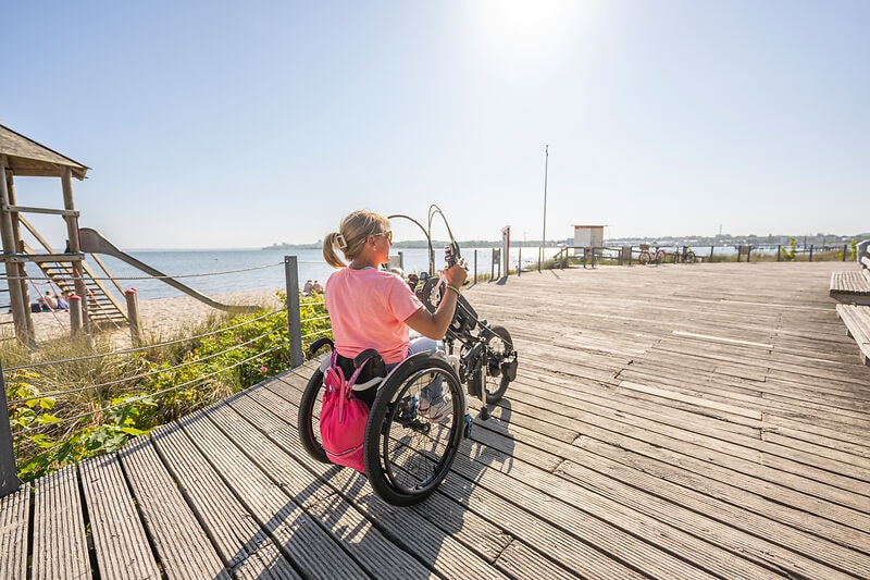 Person im Rollstuhl auf der Strandpromenade