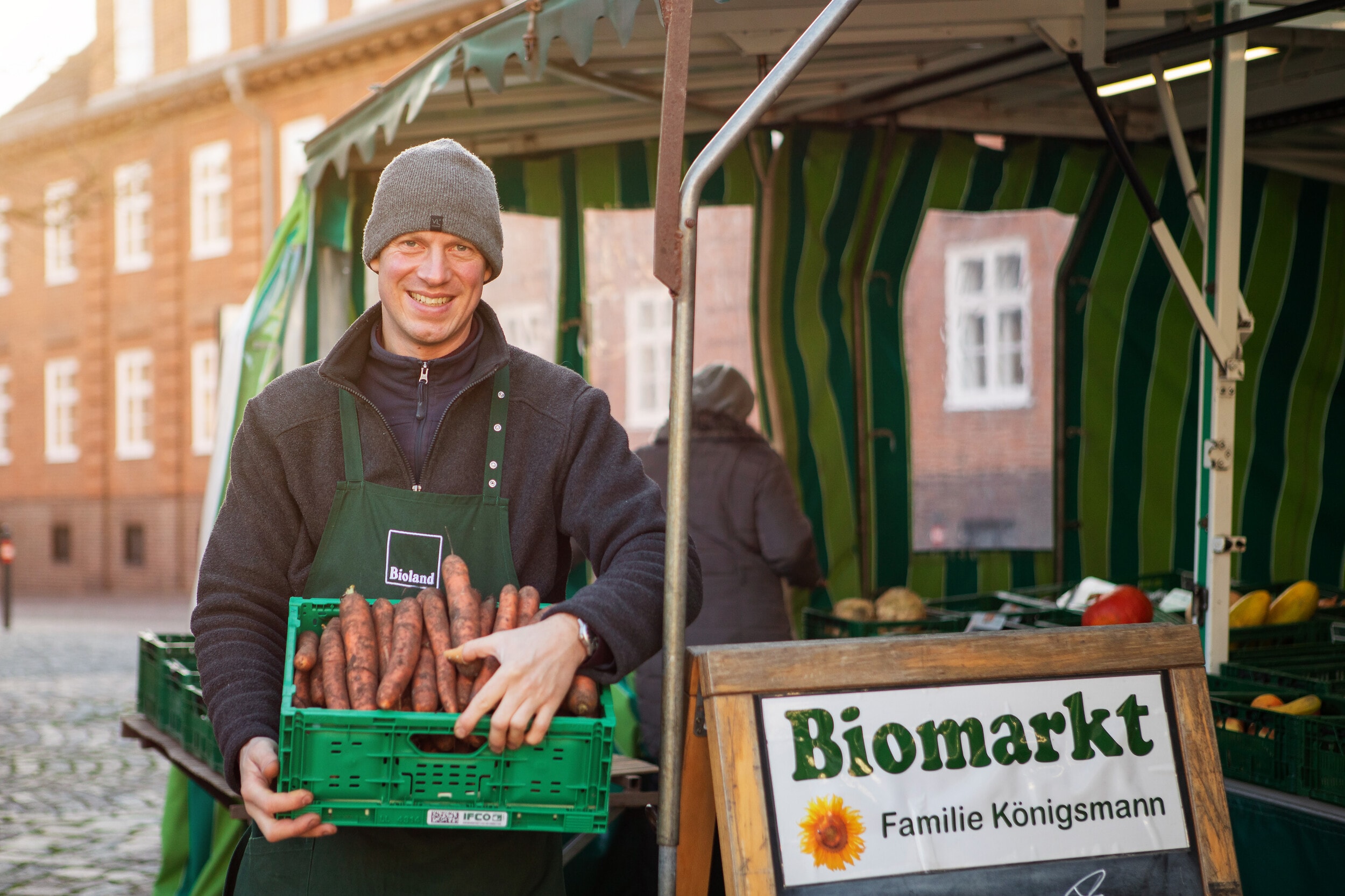 Mann hält Kiste mit Gemüse auf dem Biomarkt von Familie Königsmann in Plön